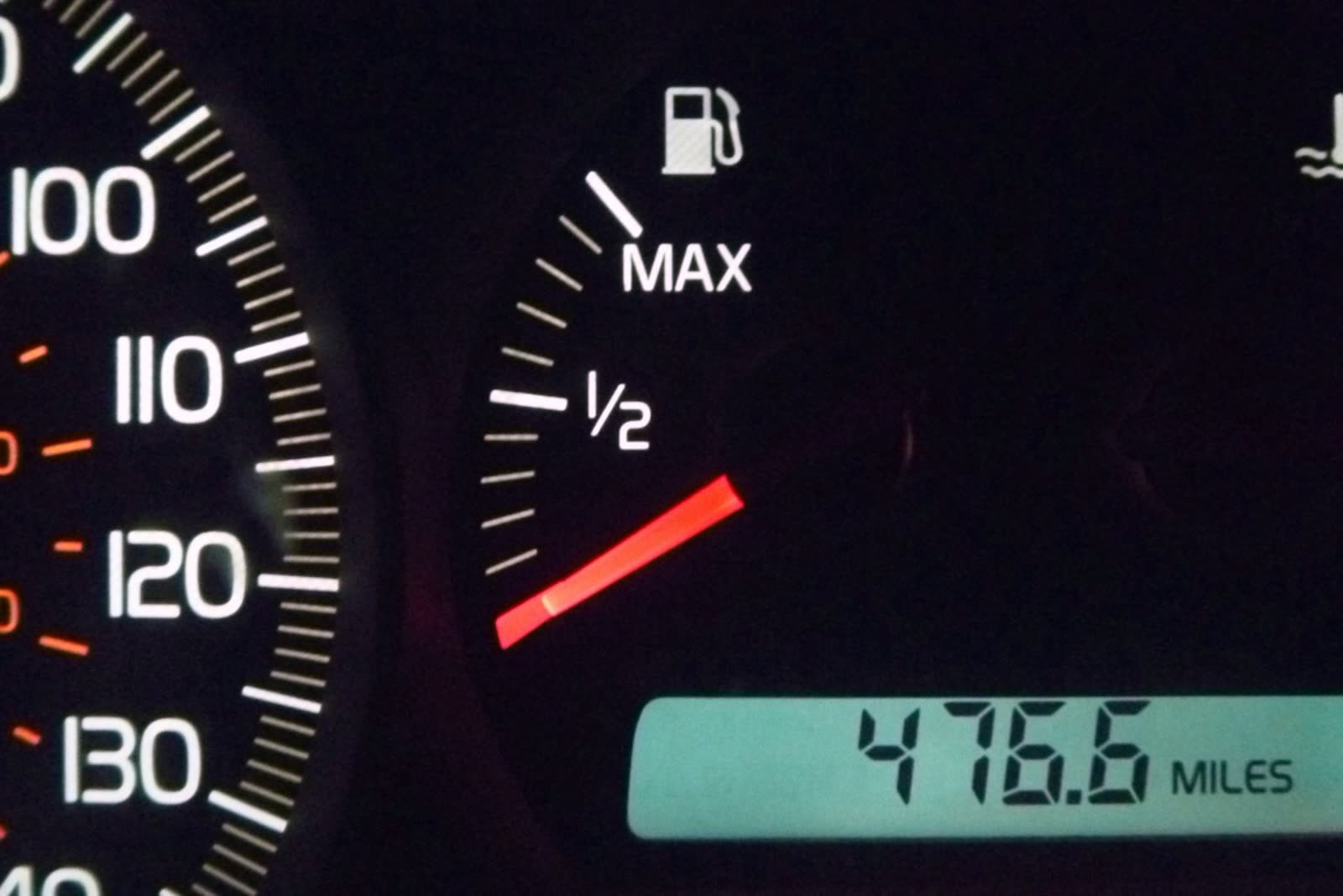 A car dashboard fuel gauge with the needle below empty and a trip counter reading 476.6 miles.